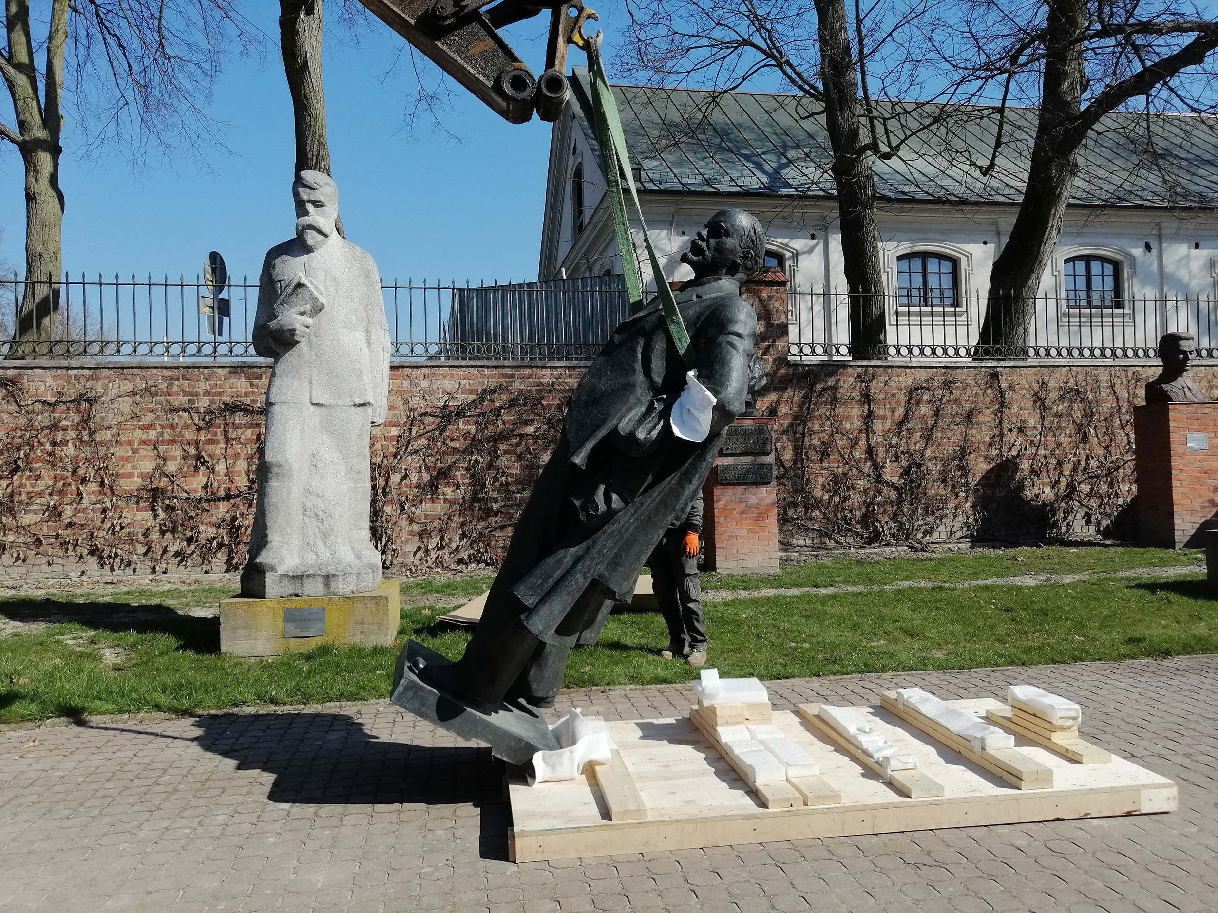 Fotografia. Pomnik Włodzimierza Lenina, postać całościowa. Rzeźba z brązu o wymiarach 260 x 120 x 75 cm podnoszona na pasach holowniczych do pozycji pionowej.