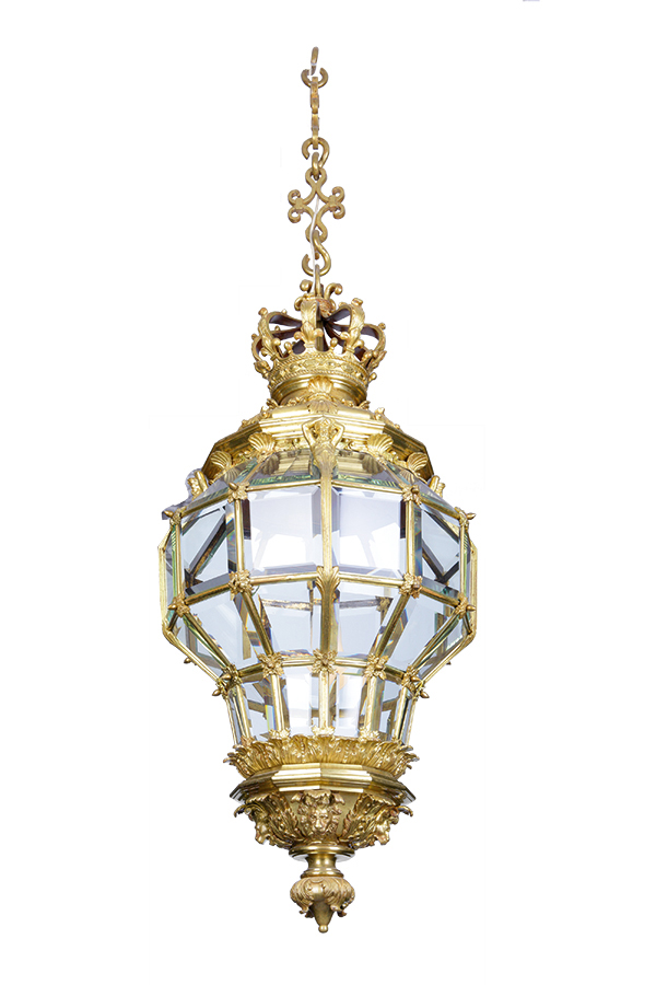 Fotografia latarni z sieni pałacu w Kozłówce, wykonana w Paryżu na przełomie XIX i XX wieku. Na białym tle złocona latarnia w formie odwróconej gruszki. Górna część udekorowana pełnoplastyczną koroną królewską. W ramkach z brązu grube szybki z fasetowanego kryształowego szkła.