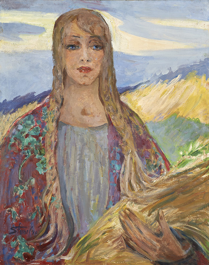 Fotografia obrazu autorstwa Stanisławy Paradowskiej-Gajewskiej, zatytułowanego W Polsce, namalowanego farbami olejnymi na płótnie około 1965 roku. Przedstawia dziewczynę w ujęciu w półpostaci, na wprost. Ma długie jasne włosy splecione w dwa warkocze opadające na piersi, jeden kosmyk przez środek czoła sięga lewej brwi. Ma podłużną twarz, o różowawej karnacji, duże niebieskie oczy, prosty nos i pełne czerwone usta. Ubrana jest w szaroniebiską bluzkę z płytkim dekoltem, na ramionach ma wzorzystą, czerwono-zieloną chustę. Lewą ręką podtrzymuje snop zboża, z którym łączą się włosy lewego warkocza. W tle widzimy falujące, żółto-zielone łany i szaroniebieskie niebo z ciemnymi pasmami chmur.